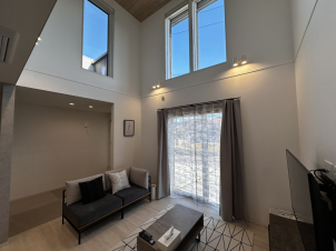 高い窓から優しい光が降りそそぐ、居心地の良い、吹抜けのあるリビングです。