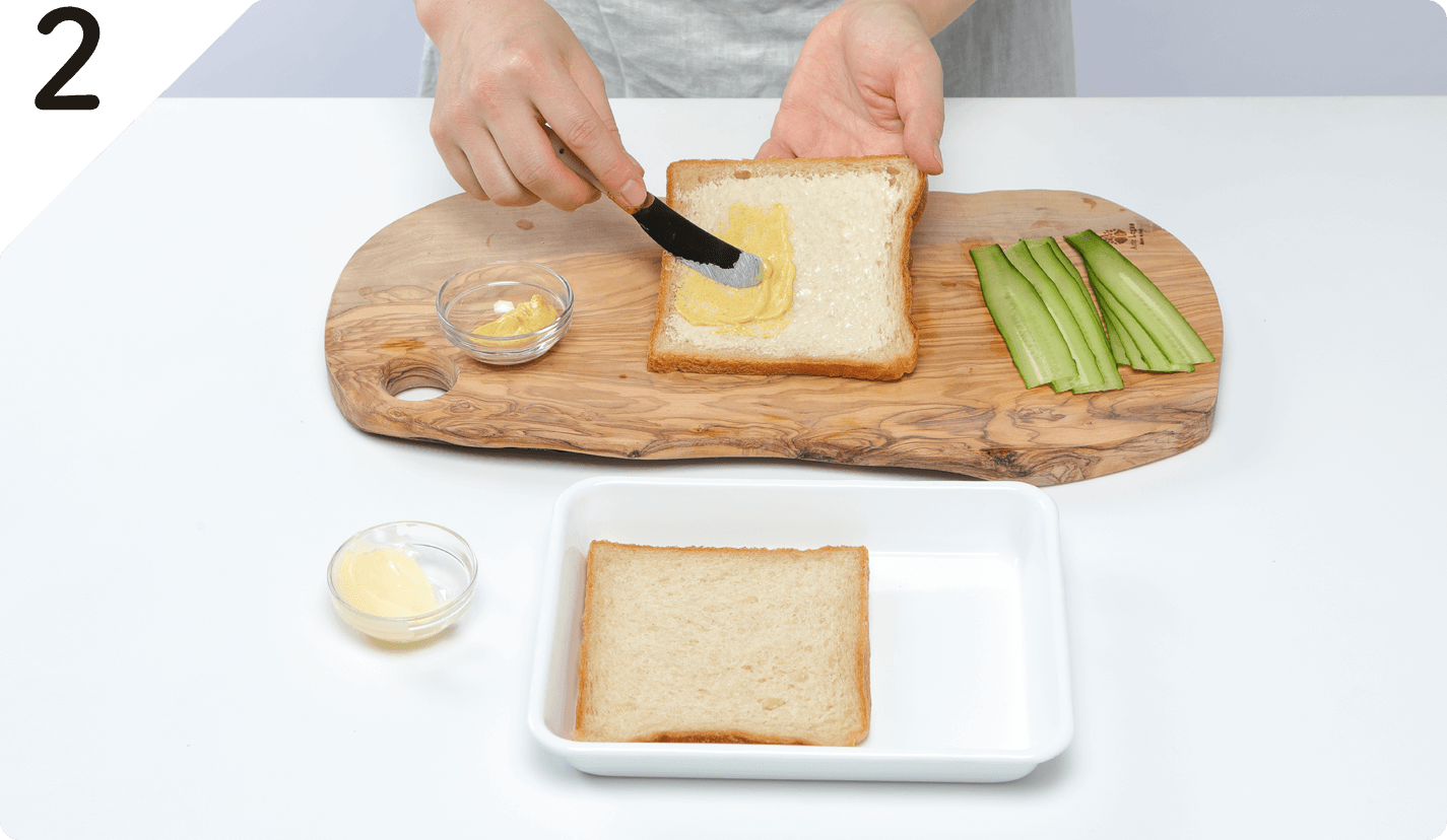 3枚の食パンの片面に薄くバターを塗り、重ねるようにマスタードも塗る。
