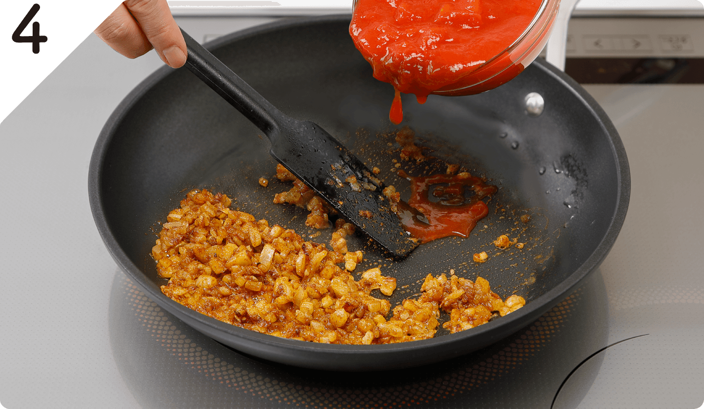 ❸ににんにく、しょうが、カレーパウダー（大さじ1）を加えて炒め、香りが出たらトマトを加え混ぜ、約5分煮詰める。