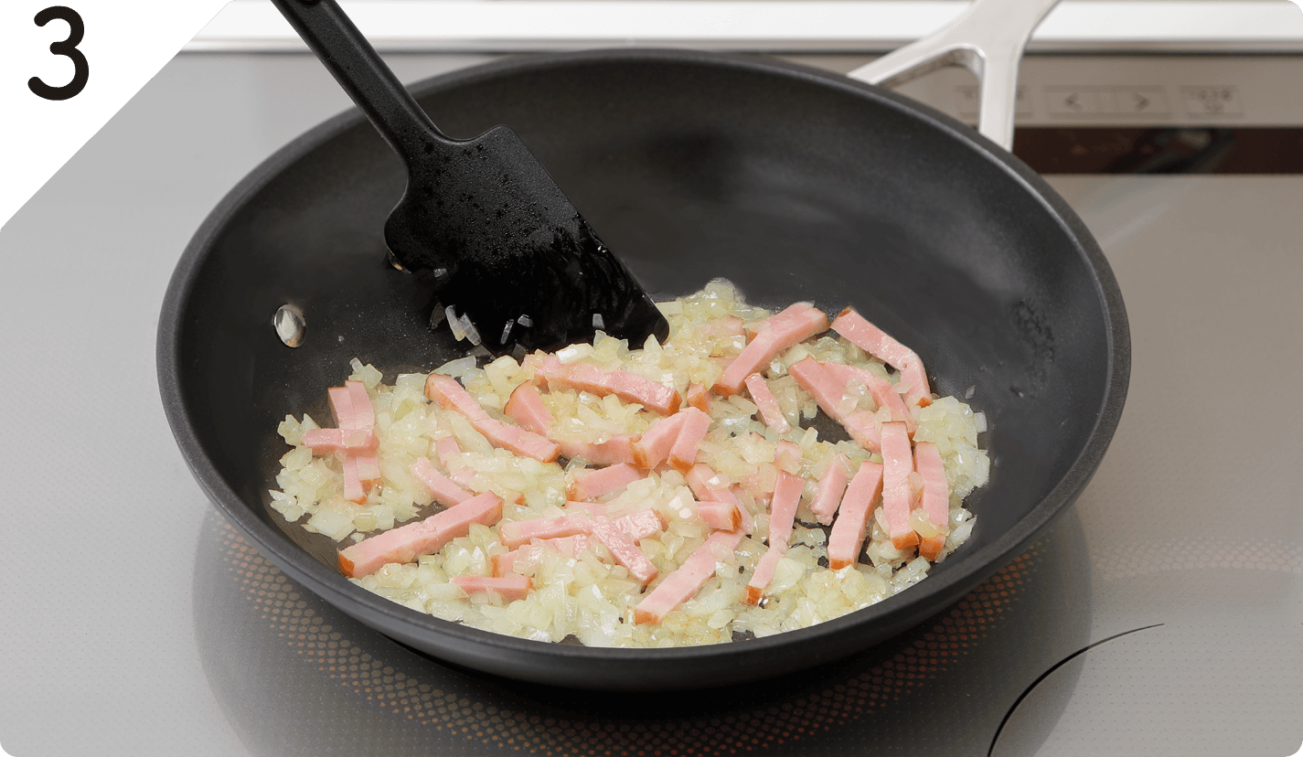 フライパンにオリーブオイル、にんにくを⼊れて中⽕で熱し、⾹りが出てきたらたまねぎを加えてしんなりするまで炒める。さらに、ベーコンを加え炒め、塩・こしょうで味をととのえ、バットに移して冷ます。