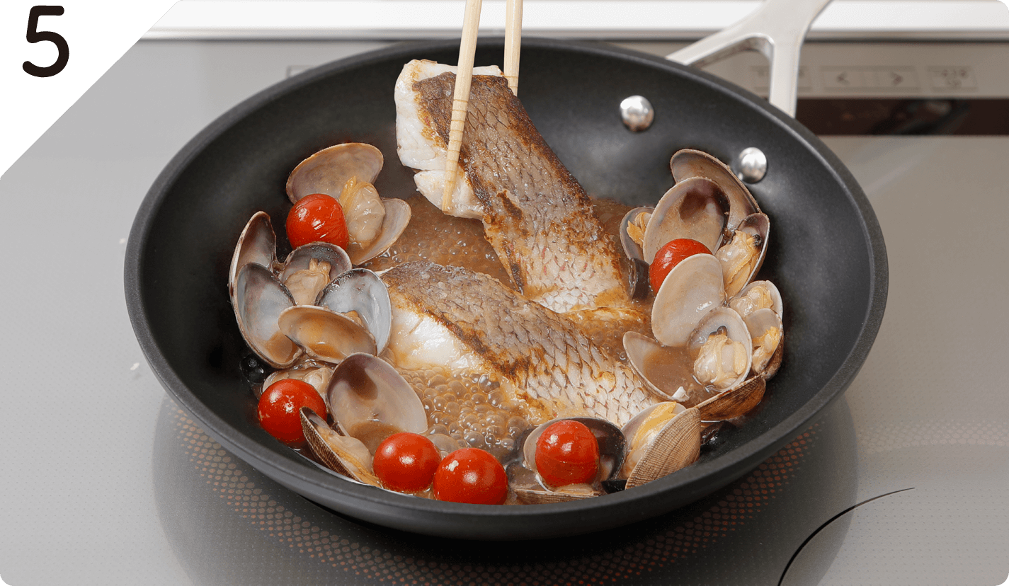 白身魚をもどし、スプーンで表面に煮汁をかけて火を止める。