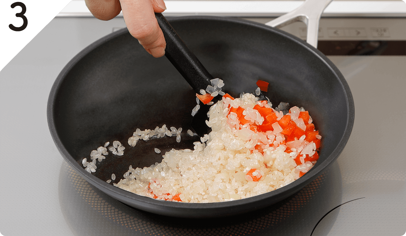 弱火にして米を加え、透き通るまで炒めたら、パプリカを加え混ぜる。
