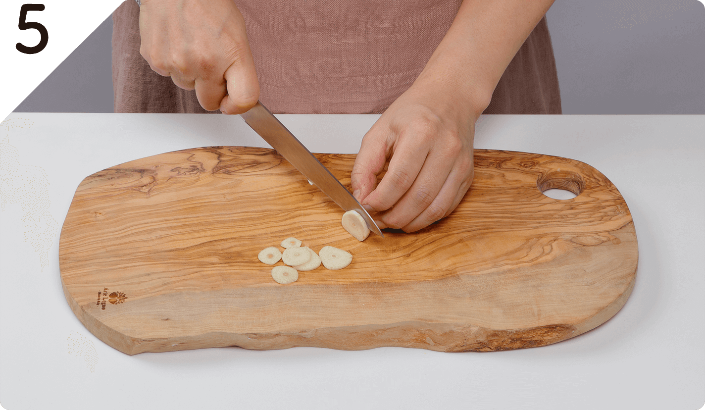 タリアータをつくる。にんにくは輪切りにする。常温に戻した牛肉に塩をふる。