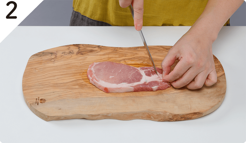 豚肉は赤身と脂身の間を数か所、包丁の刃先で刺し筋切りをして塩をふる。