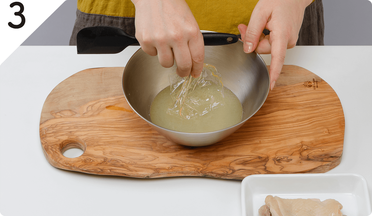 鶏肉を取り出し、煮汁はザルで別の鍋にこして再沸騰させ、ボウルに移す。そこにゼラチンを加えて溶かす。