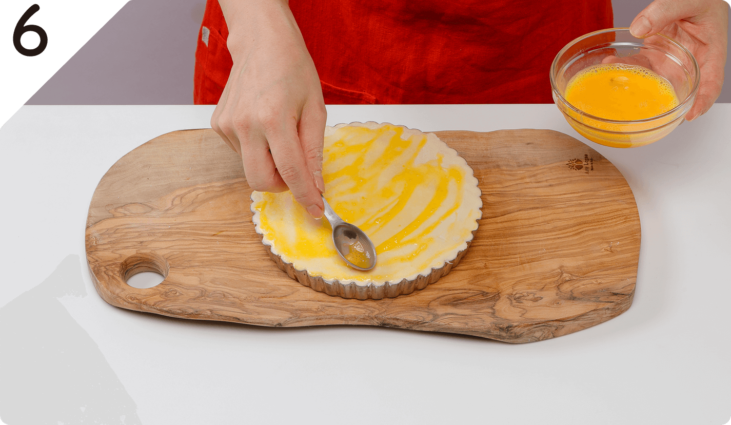 2枚の生地のふちをフォークで押さえるようにくっつけて、表面に溶き卵を薄く塗る。