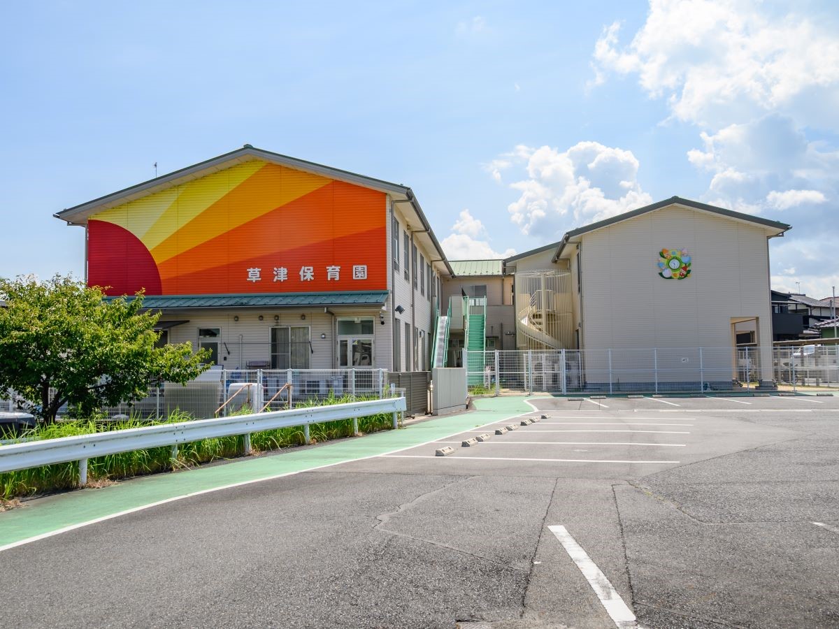 草津保育園まで約1km（徒歩13分）　園では、健康増進のために、リズム運動・素足保育・薄着等の生活・活動を行っています。野菜や植物とふれあう取り組みなどもあり、五感を通して子どもたちの感性を育んでいます。