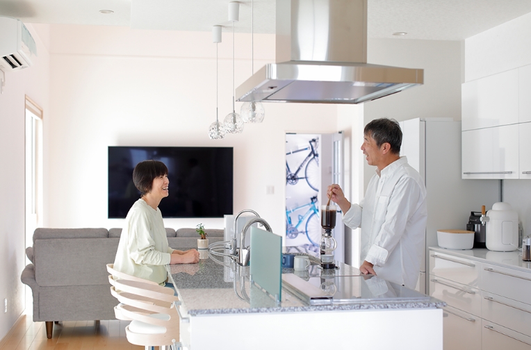 対面式キッチンでコーヒーを淹れるご夫婦。明るいリビングダイニングの様子