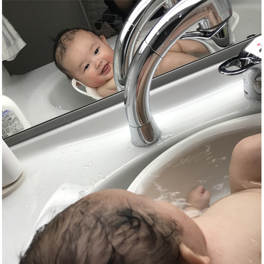 洗面台で水浴びしてる赤ちゃんの写真