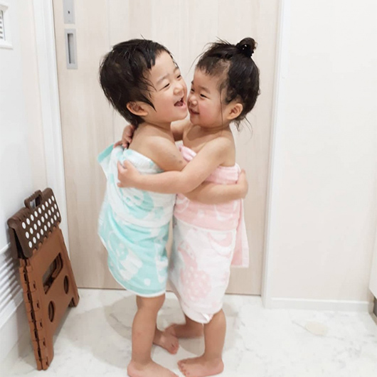 バスタオル姿で抱き合っている双子の写真