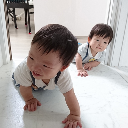 公園で空を飛んでいる飛行機に手を振っている子どもと肩車している大人の写真