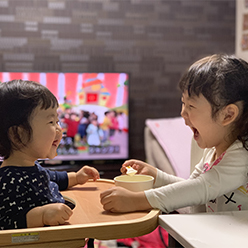 鮮やかな紫陽花が咲いている傍で、カラフルな長靴を履いた少女が水たまりの上を歩いている写真