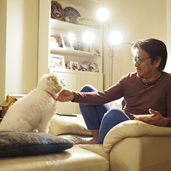 窓際にある扇風機の前で顔を近づけて涼んでいる少女の写真