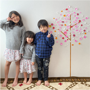 色とりどりの折り紙で桜の木を壁に作ってお花見をしている子どもたちの写真