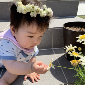 花冠をかぶった子どもがお花を眺めている写真