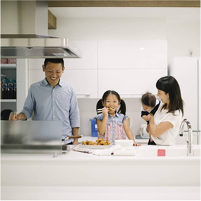 キッチンでつまみ食いしている子どもと微笑んでいる家族の写真
