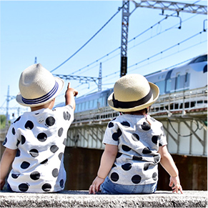 石垣に座りながら電車を見ている二人の子どもの写真