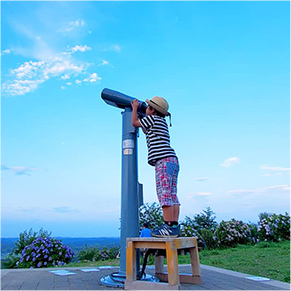 晴れた空の中望遠鏡を覗いている子どもの写真