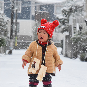 街中で雪を見て驚き泣いている子どもの写真