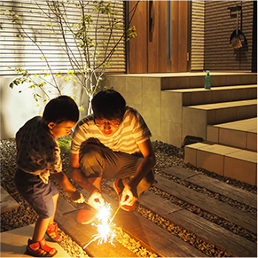 家の前で花火をしている親子の写真