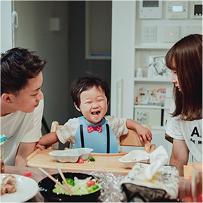 リビングで和気藹々と食事をしている家族の写真